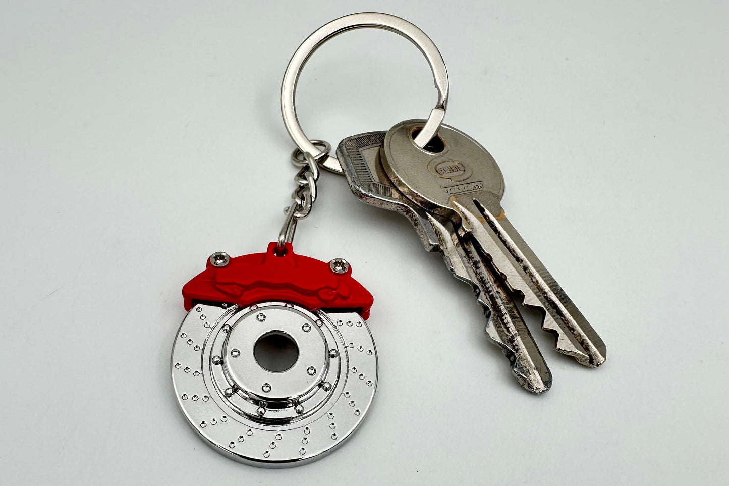 Keychain with brake rotor design and red accents on a white background
