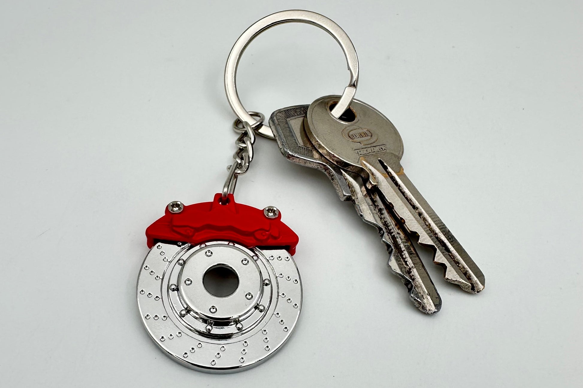 Keychain with brake rotor design and red accents on a white background